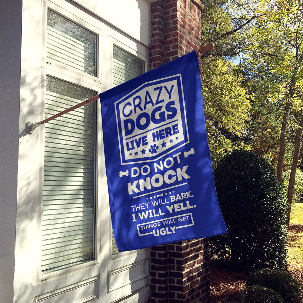 blue house flag hung up on wall with text "crazy dogs live here do not knock they will bark, i will yell, things will get ugly"
