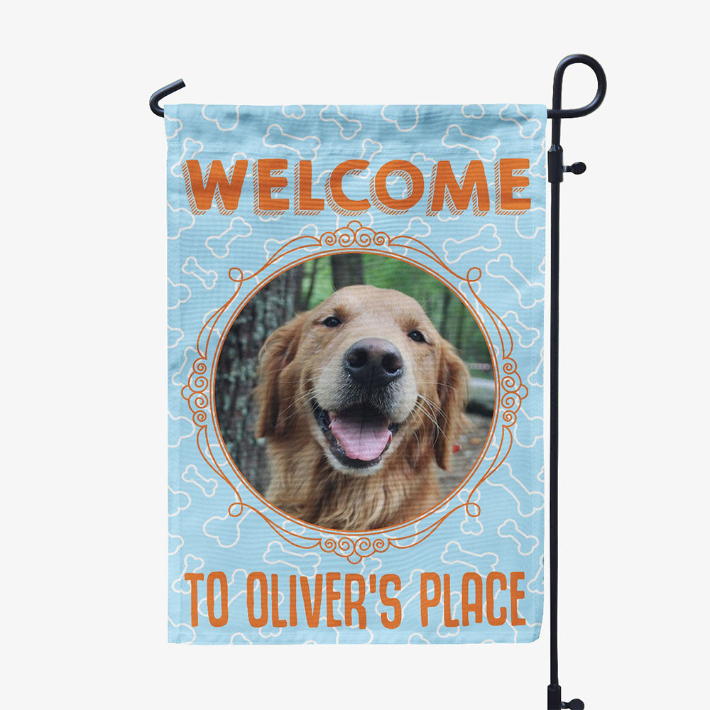 blue garden flag with text "welcome to oliver's place" with image of dog in circular frame
