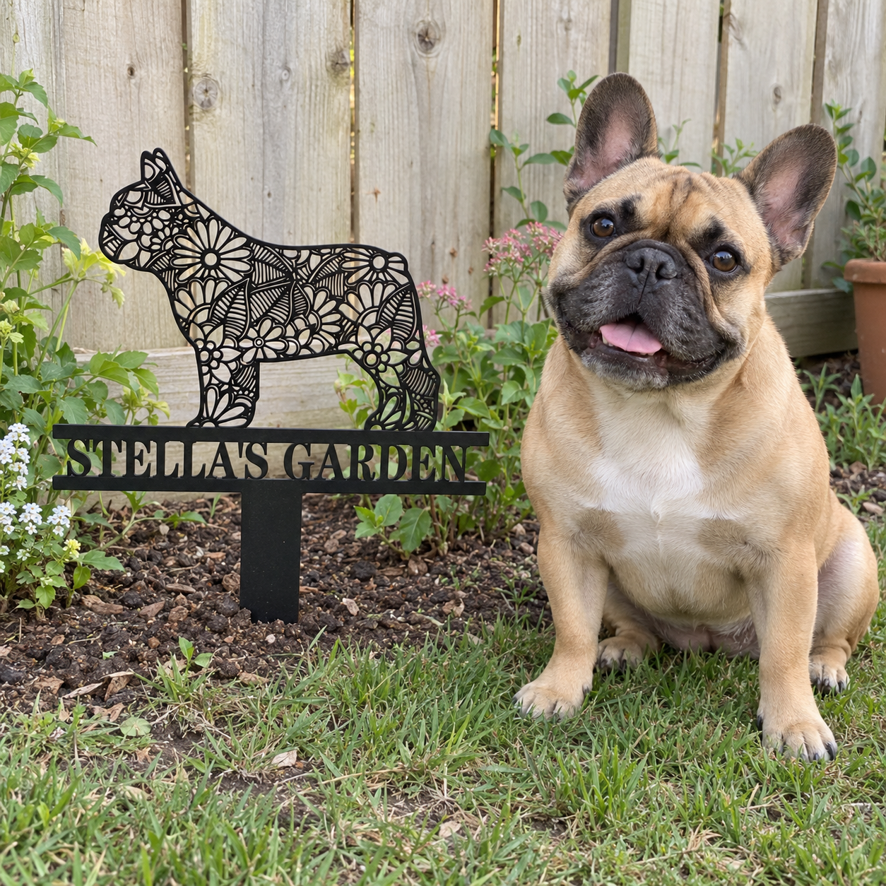 French Bulldog sitting beside a garden stake personalized with Stella’s Garden
