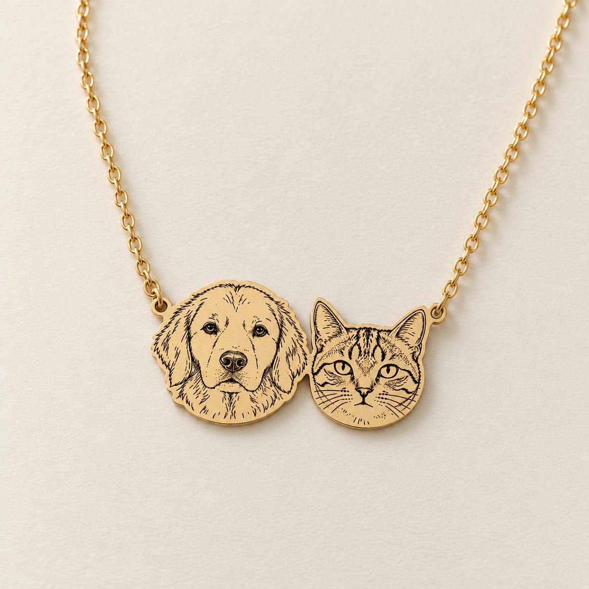 Illustrated gold-colored necklace with connected retriever and tabby portraits on a fine chain.