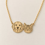 Illustrated gold-colored necklace with connected retriever and tabby portraits on a fine chain.