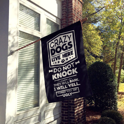 black house flag hung up on wall with text "crazy dogs live here do not knock they will bark, i will yell, things will get ugly"