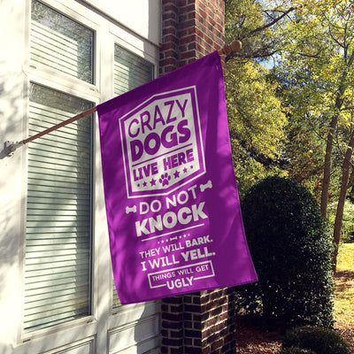 purple house flag hung up on wall with text "crazy dogs live here, do not knock, they will bark, I will yell, things will get ugly"